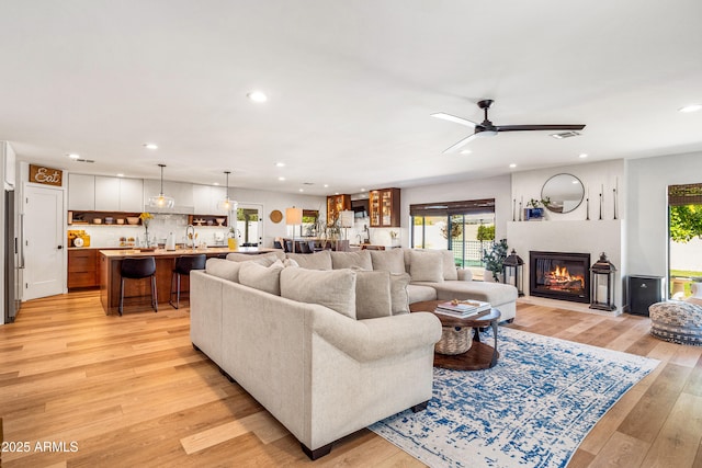 living room with light wood finished floors, a ceiling fan, visible vents, a glass covered fireplace, and recessed lighting