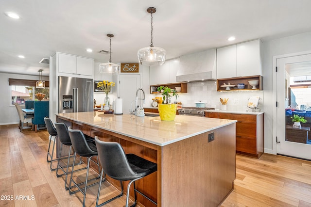 kitchen with white cabinets, appliances with stainless steel finishes, light wood finished floors, and a sink