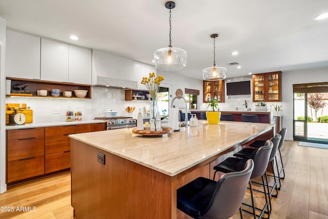 kitchen with high end stainless steel range oven, open shelves, a kitchen island with sink, and plenty of natural light