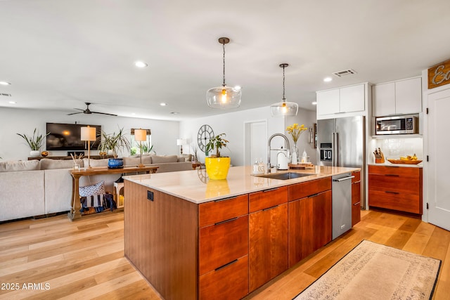 kitchen featuring visible vents, open floor plan, appliances with stainless steel finishes, and a sink