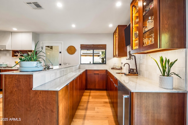 kitchen with brown cabinets, a sink, visible vents, backsplash, and recessed lighting
