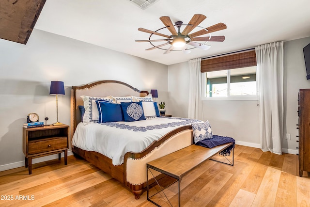 bedroom with light wood finished floors, visible vents, baseboards, and a ceiling fan