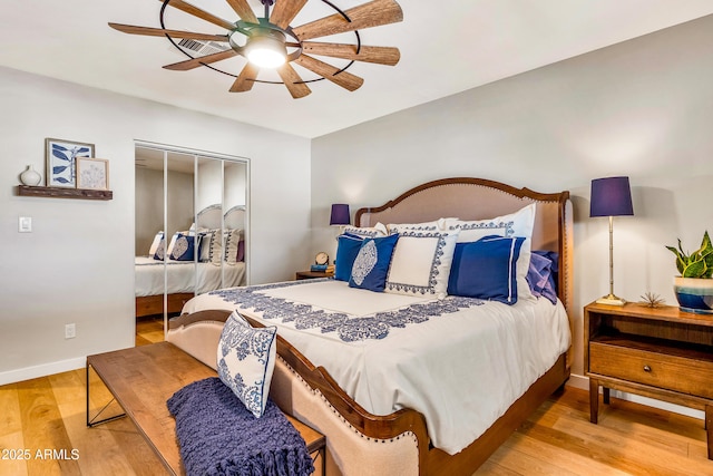 bedroom featuring a closet, wood finished floors, visible vents, a ceiling fan, and baseboards