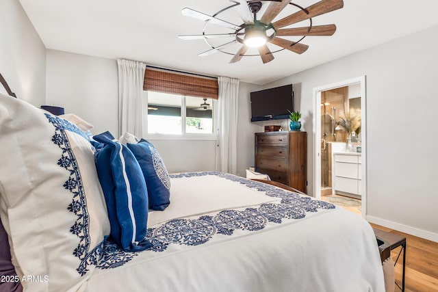 bedroom with baseboards, ensuite bathroom, a ceiling fan, and wood finished floors