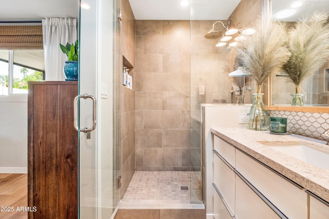 bathroom with vanity, a shower stall, and backsplash