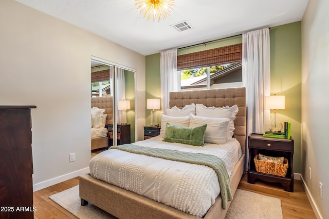 bedroom with baseboards, multiple windows, visible vents, and wood finished floors