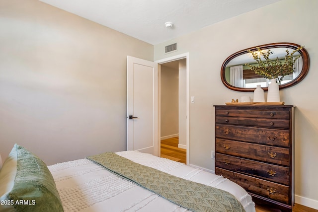bedroom with wood finished floors, visible vents, and baseboards