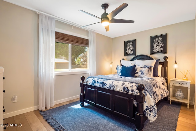 bedroom with a ceiling fan, wood finished floors, and baseboards
