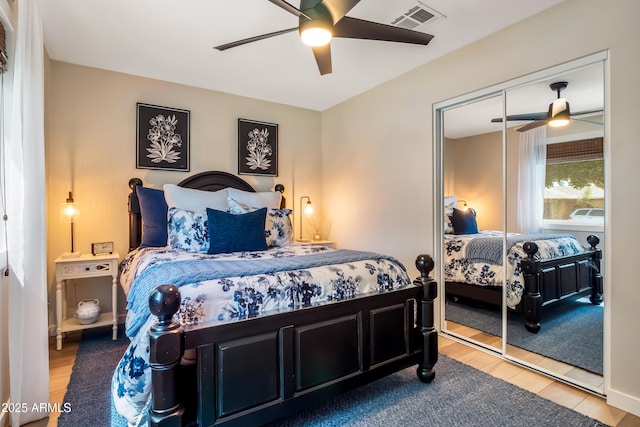 bedroom featuring a closet, a ceiling fan, visible vents, and wood finished floors