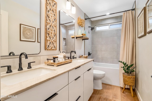 full bath featuring toilet, shower / tub combo with curtain, a sink, and wood finished floors