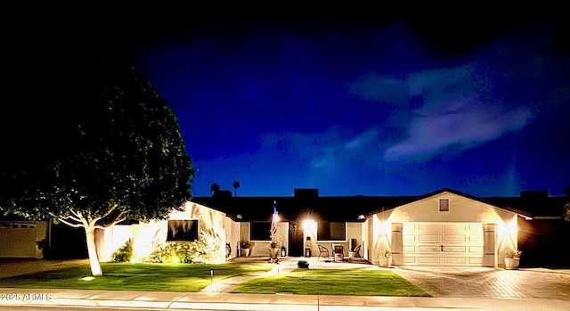 ranch-style house featuring a lawn, driveway, stucco siding, and a garage