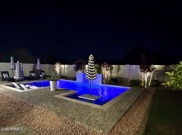 pool at night with a fenced backyard, a patio area, and a fenced in pool