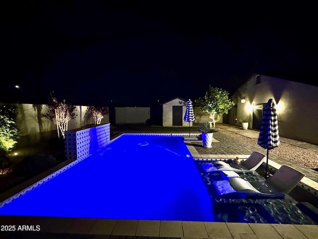 pool at twilight with a fenced backyard and an outdoor pool