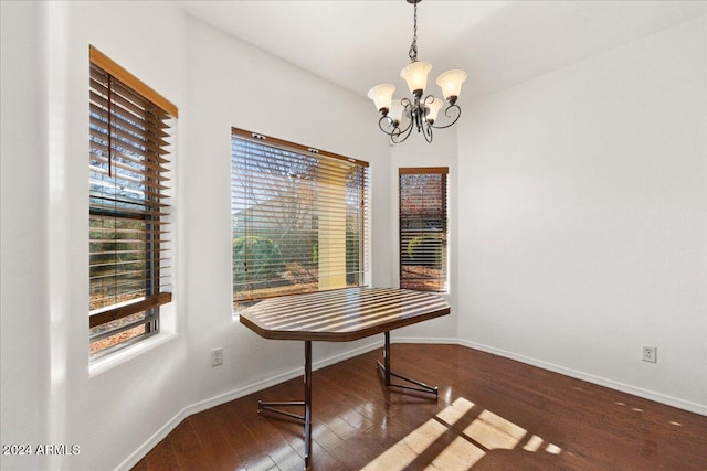 dining area with dark hardwood / wood-style flooring, an inviting chandelier, and plenty of natural light