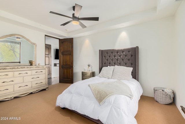 bedroom featuring a raised ceiling, ceiling fan, and light colored carpet