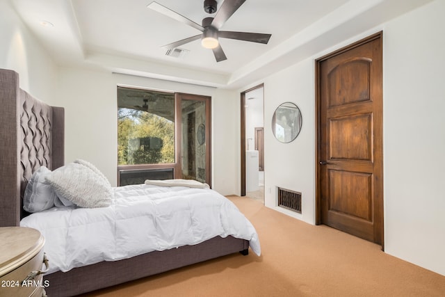 bedroom featuring a raised ceiling, ceiling fan, and light colored carpet