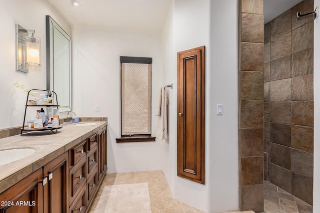 bathroom with tiled shower, vanity, and tile patterned floors