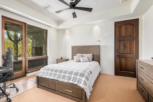 carpeted bedroom with a raised ceiling and ceiling fan