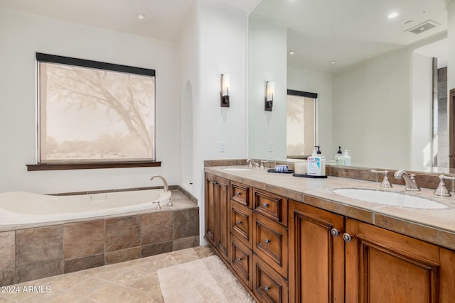 bathroom with tile patterned flooring, vanity, and tiled tub