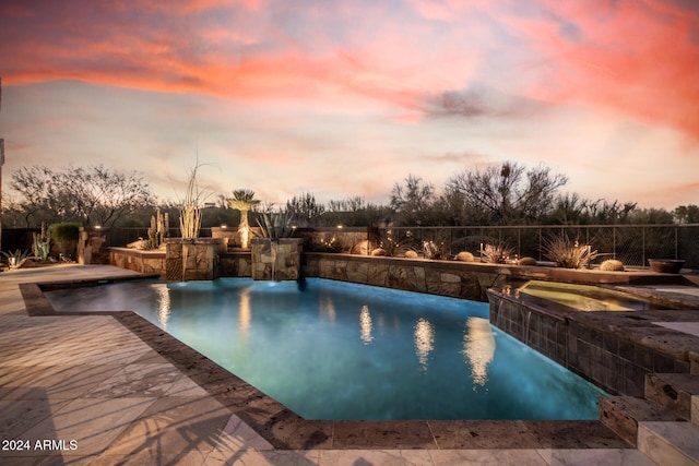 pool at dusk with pool water feature and a patio