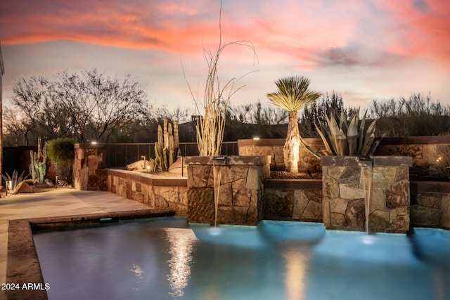 pool at dusk with a patio area