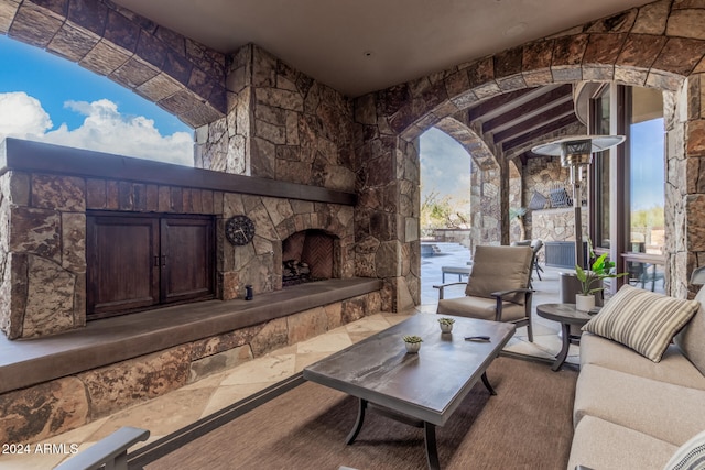 living room with an outdoor stone fireplace and lofted ceiling