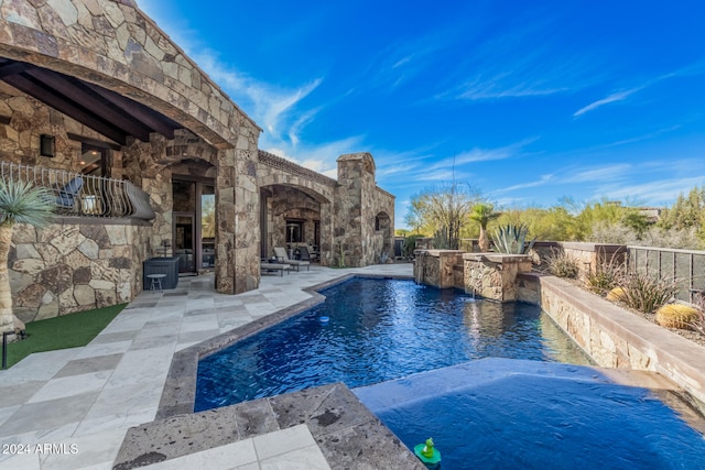 view of pool with a patio area, pool water feature, and exterior fireplace