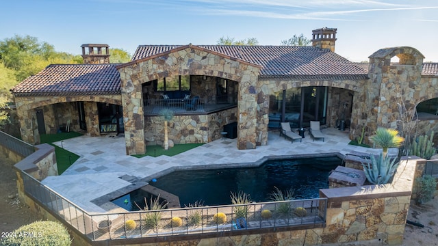 back of property featuring a fenced in pool, a fireplace, and a patio