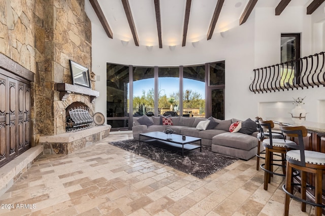 living room with beam ceiling, a fireplace, and a high ceiling