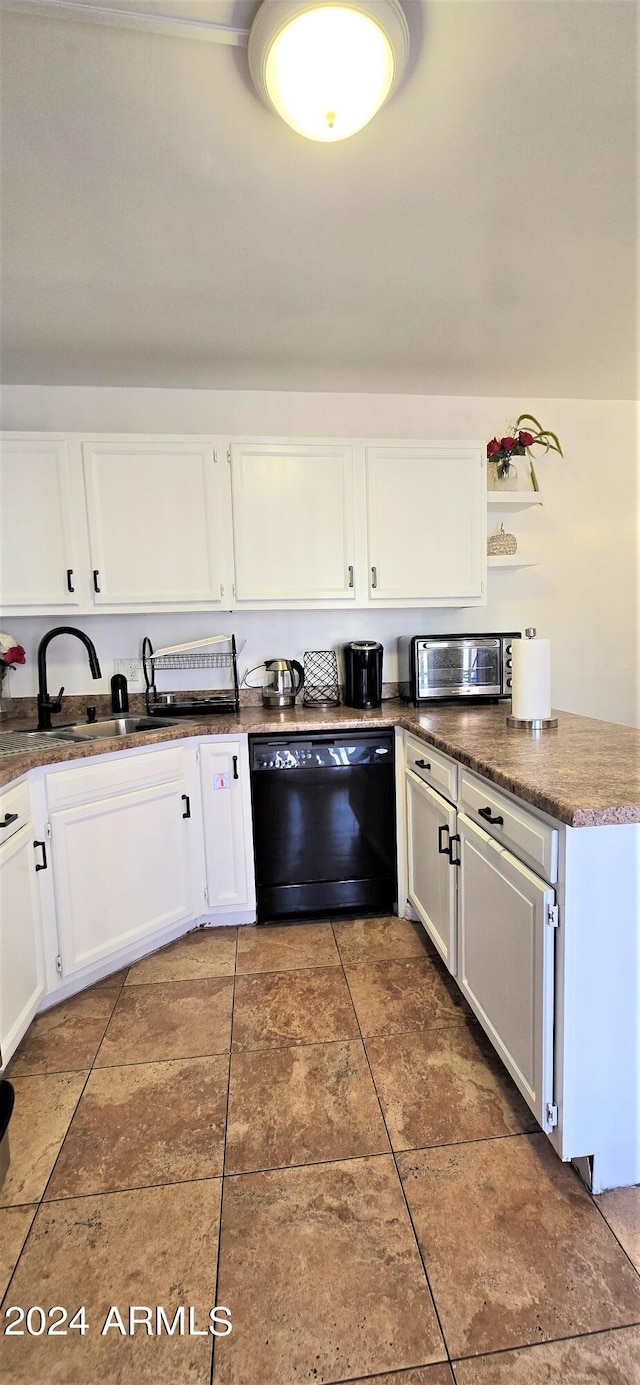 kitchen with dark tile patterned flooring, black dishwasher, white cabinetry, and sink