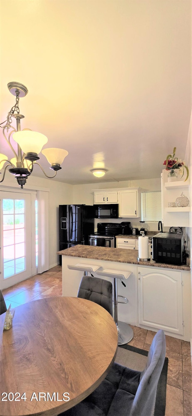 kitchen with white cabinets, a notable chandelier, black appliances, kitchen peninsula, and a kitchen breakfast bar