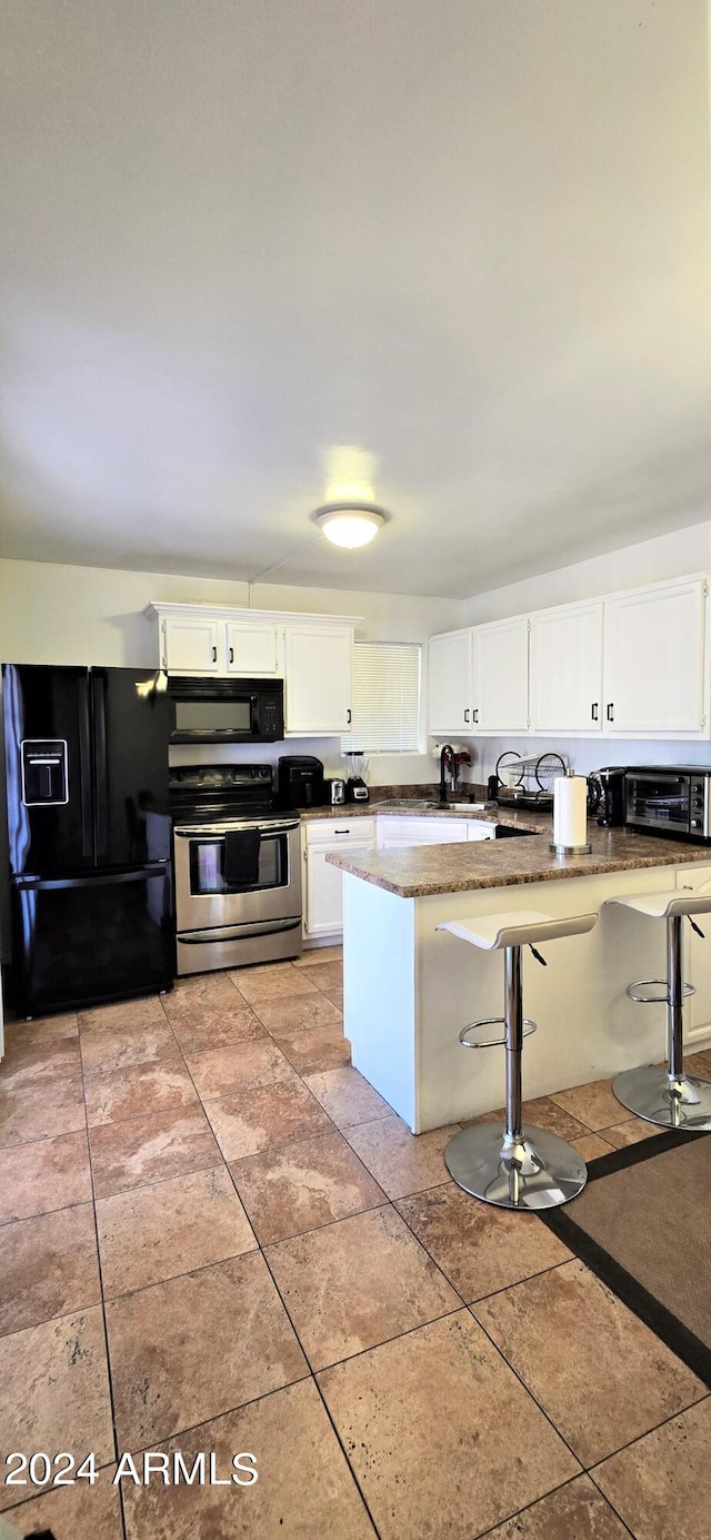 kitchen featuring a breakfast bar area, black appliances, light tile patterned floors, kitchen peninsula, and white cabinetry