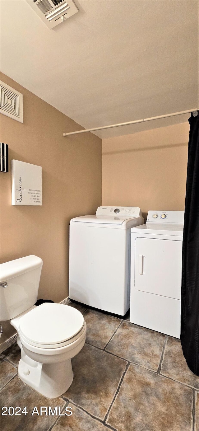 bathroom with toilet, washing machine and dryer, and tile patterned flooring