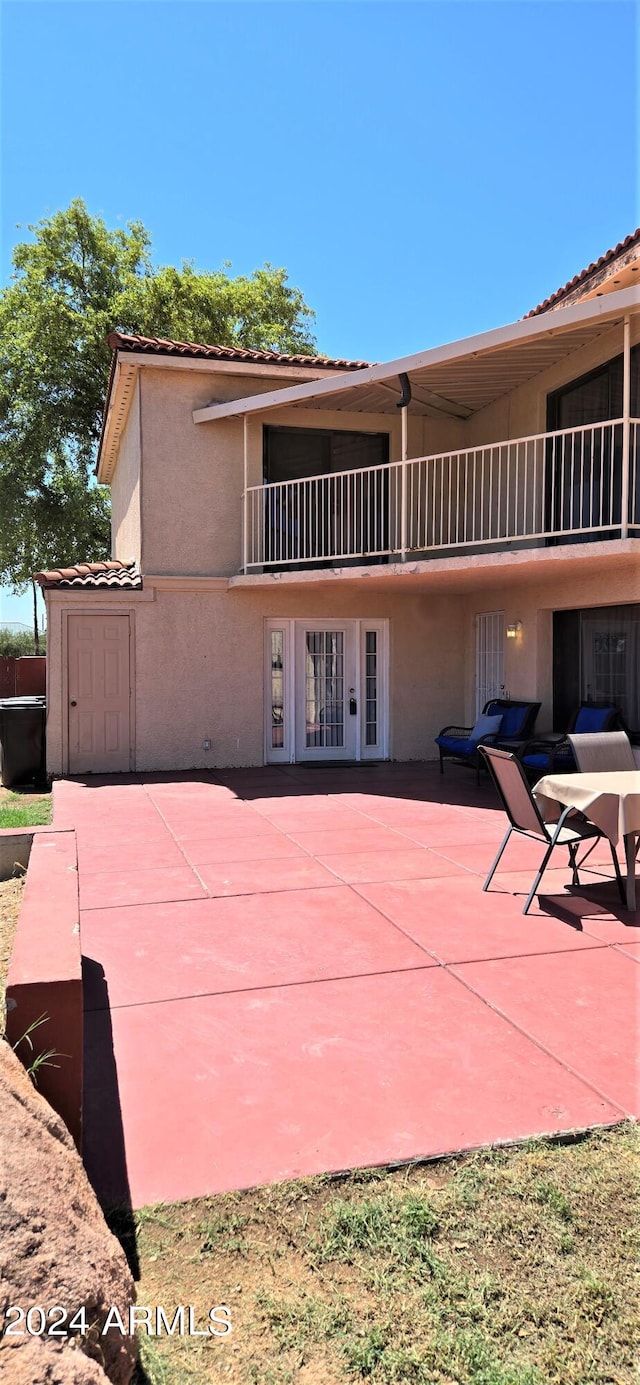 back of property featuring a patio, a balcony, and french doors