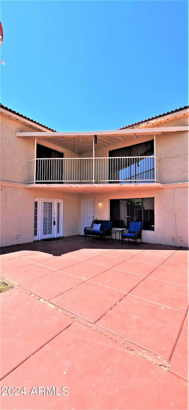 rear view of property with a balcony, french doors, and a patio area