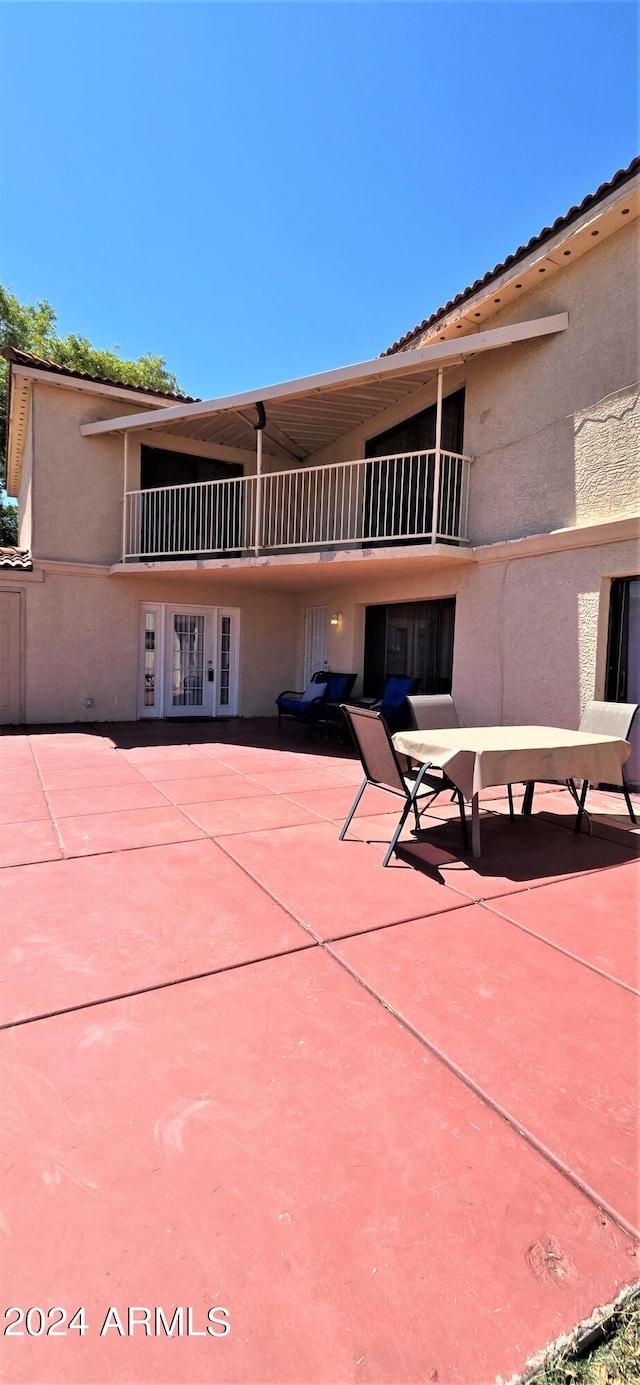 back of property featuring a patio, a balcony, and french doors