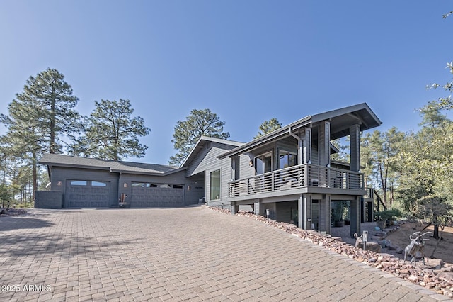 view of property exterior featuring an attached garage, decorative driveway, and a balcony