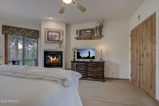 carpeted bedroom with a glass covered fireplace, a ceiling fan, baseboards, and access to outside