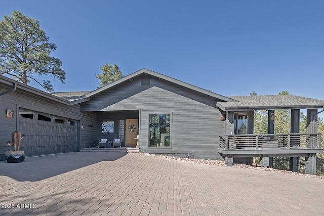 view of front of property with decorative driveway, roof with shingles, and an attached garage