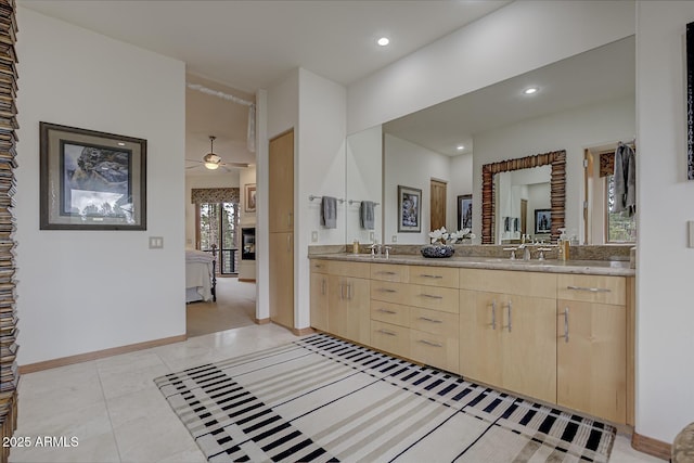 bathroom with double vanity, baseboards, ensuite bathroom, and a sink