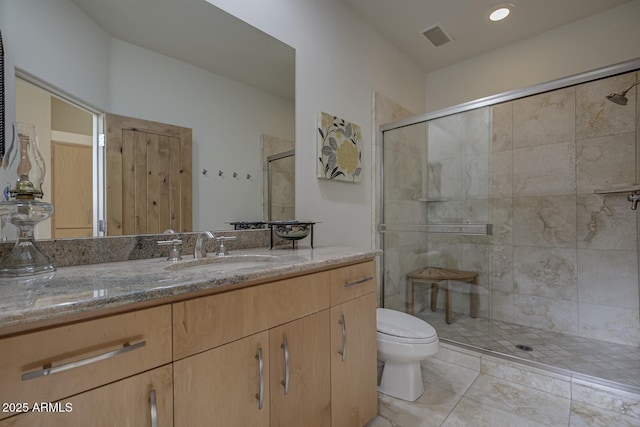 full bath featuring vanity, a shower stall, toilet, and visible vents