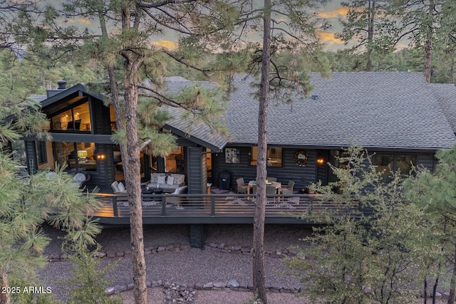 rear view of house featuring a wooden deck, an outdoor hangout area, and a shingled roof