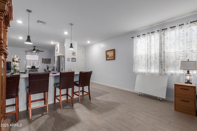 1463 W Pinkley Ave, Coolidge, AZ 85128 - kitchen featuring freestanding refrigerator, a ceiling fan, a kitchen breakfast bar, wood finished floors, and recessed lighting