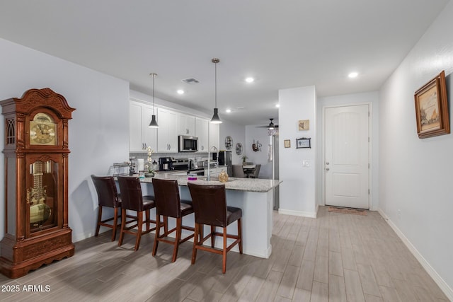 1463 W Pinkley Ave, Coolidge, AZ 85128 - kitchen featuring appliances with stainless steel finishes, light wood-style floors, white cabinets, a peninsula, and decorative backsplash