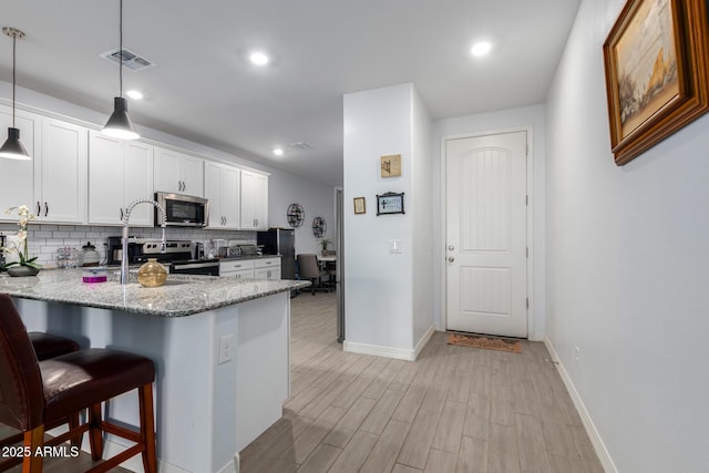 1463 W Pinkley Ave, Coolidge, AZ 85128 - kitchen with appliances with stainless steel finishes, decorative backsplash, a peninsula, a kitchen breakfast bar, and white cabinets