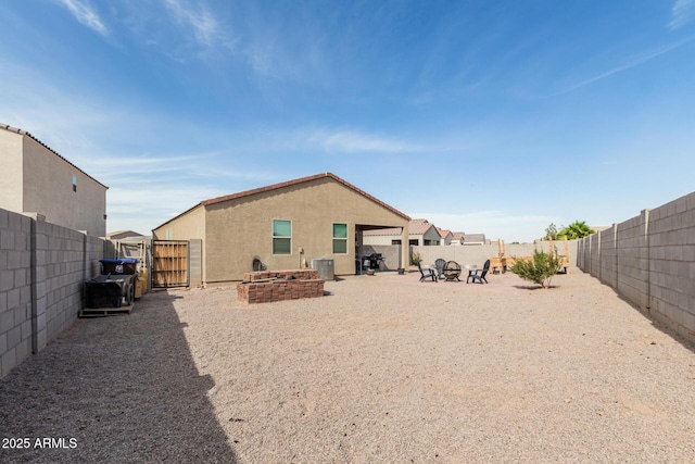 1463 W Pinkley Ave, Coolidge, AZ 85128 - rear view of house featuring a gate, a fenced backyard, stucco siding, an outdoor fire pit, and central air condition unit