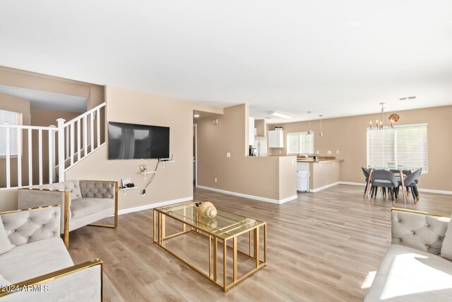 living room with a notable chandelier, light hardwood / wood-style floors, and a wealth of natural light