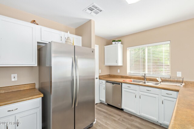 kitchen with white cabinets, light hardwood / wood-style flooring, sink, and stainless steel appliances