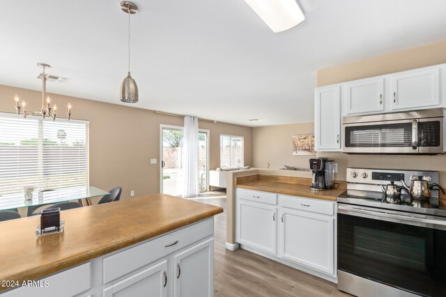 kitchen featuring a notable chandelier, decorative light fixtures, white cabinetry, and stainless steel appliances