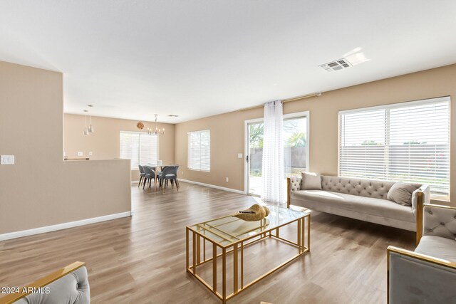 living room featuring plenty of natural light, a chandelier, and light wood-type flooring